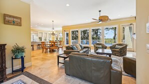 A spacious living area with a large sofa, a dining table, and a kitchen in the background. - 18 Sand Dollar, Oceanfront, Pool, Free Golf, Elevator, Great Views (Hilton Head Island)