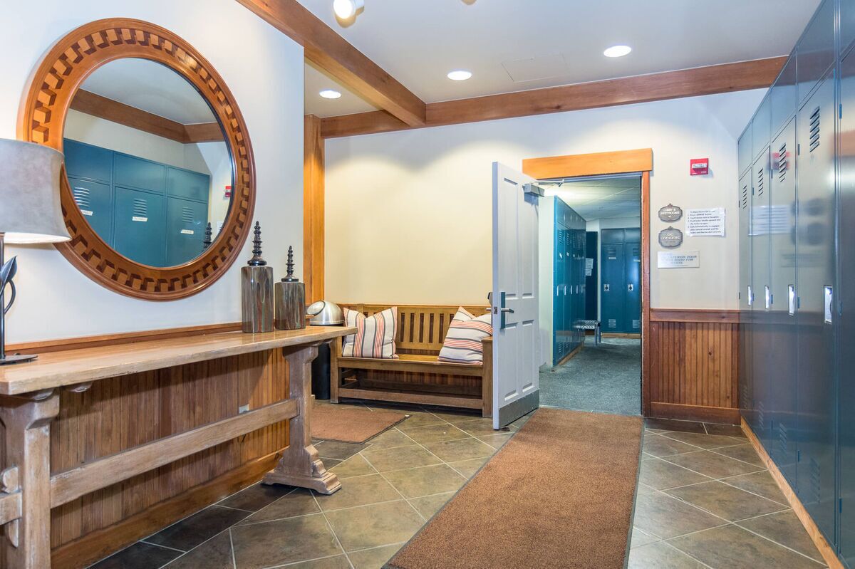 A reception area with a wooden bench, a large mirror, and a bench with pillows.