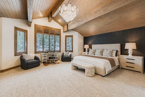 A bedroom with a large bed, two bedside tables, a desk, and a chair.