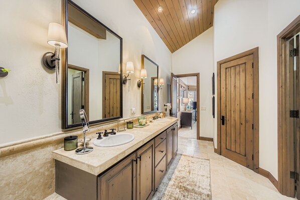 A bathroom with a double sink vanity, large mirrors, and a wooden ceiling.