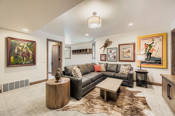 A modern living room with a sectional sofa, a coffee table, a rug, and wall art.