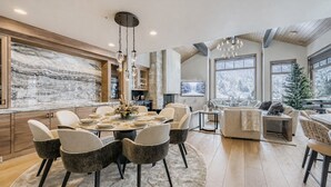 A spacious living area with a large dining table, comfortable seating, and a fireplace.