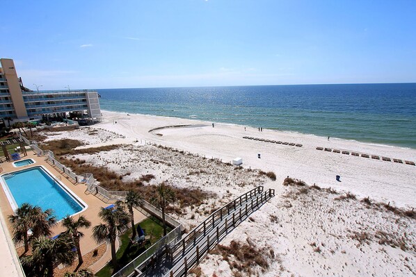 A beach resort with a swimming pool, beach access, and a view of the ocean.