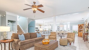 A spacious living room with a brown sofa, a wicker ottoman, and a ceiling fan. - Driftaway | Ocean Views, Dual Sun Rooms (Tybee Island)