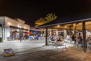 Enjoy al fresco dining with a view of the waterfront from this outdoor dining area, featuring comfortable seating and umbrellas for shade.
