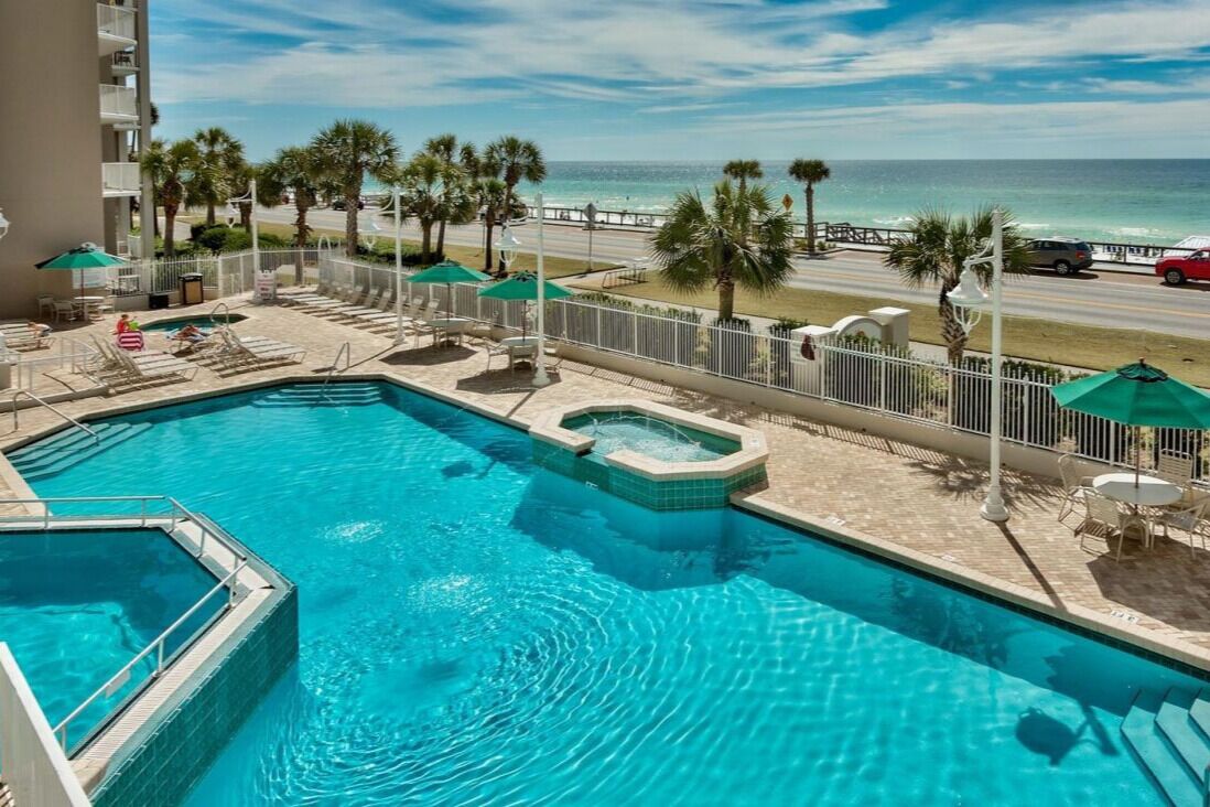 Una piscina con lettini e ombrelloni, una vasca idromassaggio e vista sulla spiaggia e sull'oceano.