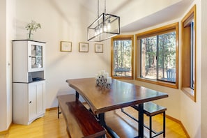 Enjoy meals together at this dining area with a large table and benches, surrounded by serene views of the outdoors.