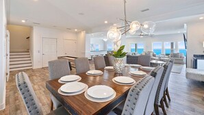 Une salle à manger spacieuse avec une grande table en bois, dressée pour six personnes, entourée de chaises rembourrées.