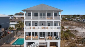 Une propriété en bord de mer, composée de plusieurs étages, dotée de balcons, d’une piscine et d’un espace salon extérieur.