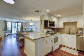 A modern kitchen with white cabinetry, a microwave, stove, and a sink.