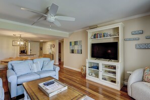 A living room with a sofa, coffee table, TV, and a ceiling fan.