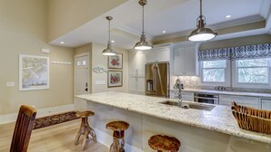 A kitchen with a large island, pendant lights, and a refrigerator. - 231 Beachside Homes-3 min walk to the beach (352 yards) or South Beach Marina (Hilton Head Island)