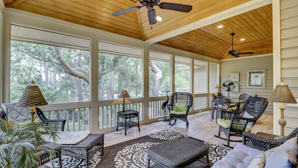 A covered porch with wicker furniture, large windows, ceiling fans, and a view of trees. - 231 Beachside Homes-3 min walk to the beach (352 yards) or South Beach Marina (Hilton Head Island)