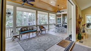 A spacious porch with a ceiling fan, wooden beams, and large windows offering views of trees. - 231 Beachside Homes-3 min walk to the beach (352 yards) or South Beach Marina (Hilton Head Island)