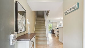 A hallway leading to a staircase with a sign reading "BEACH HOUSE".
