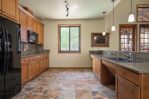 Una cocina amplia con armarios de madera, encimera de granito y un gran ventanal que aporta luz natural.