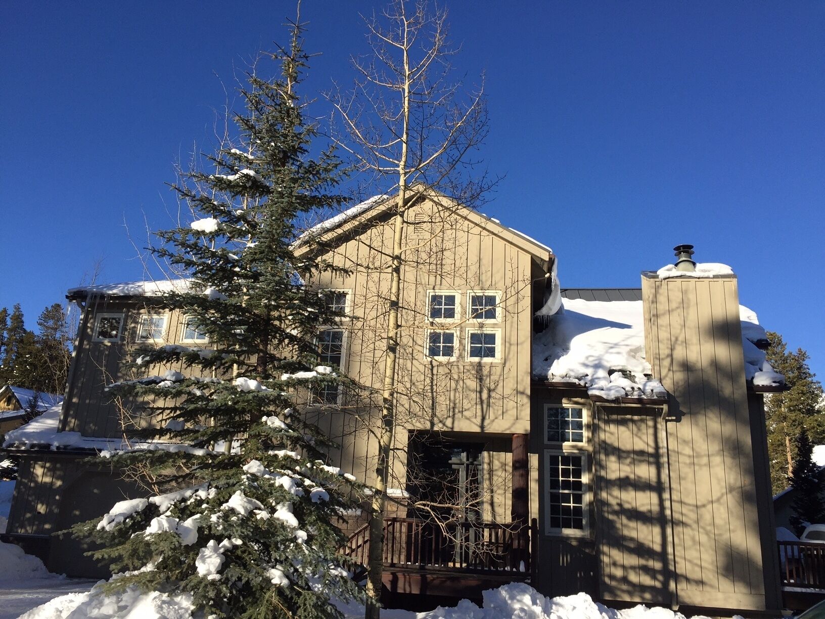 A two-story house with a snow-covered roof and a chimney.