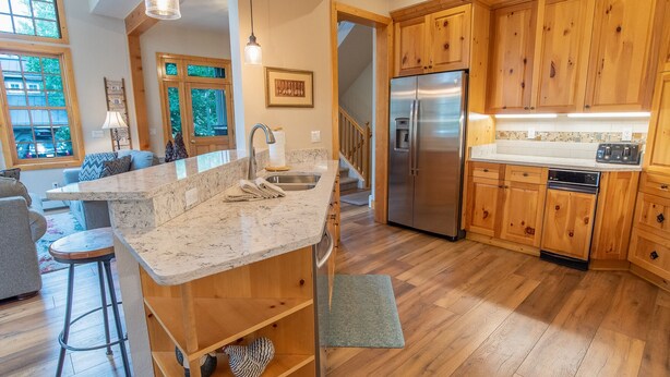 Una cocina con armarios de madera, un refrigerador de acero inoxidable y una encimera de mármol.