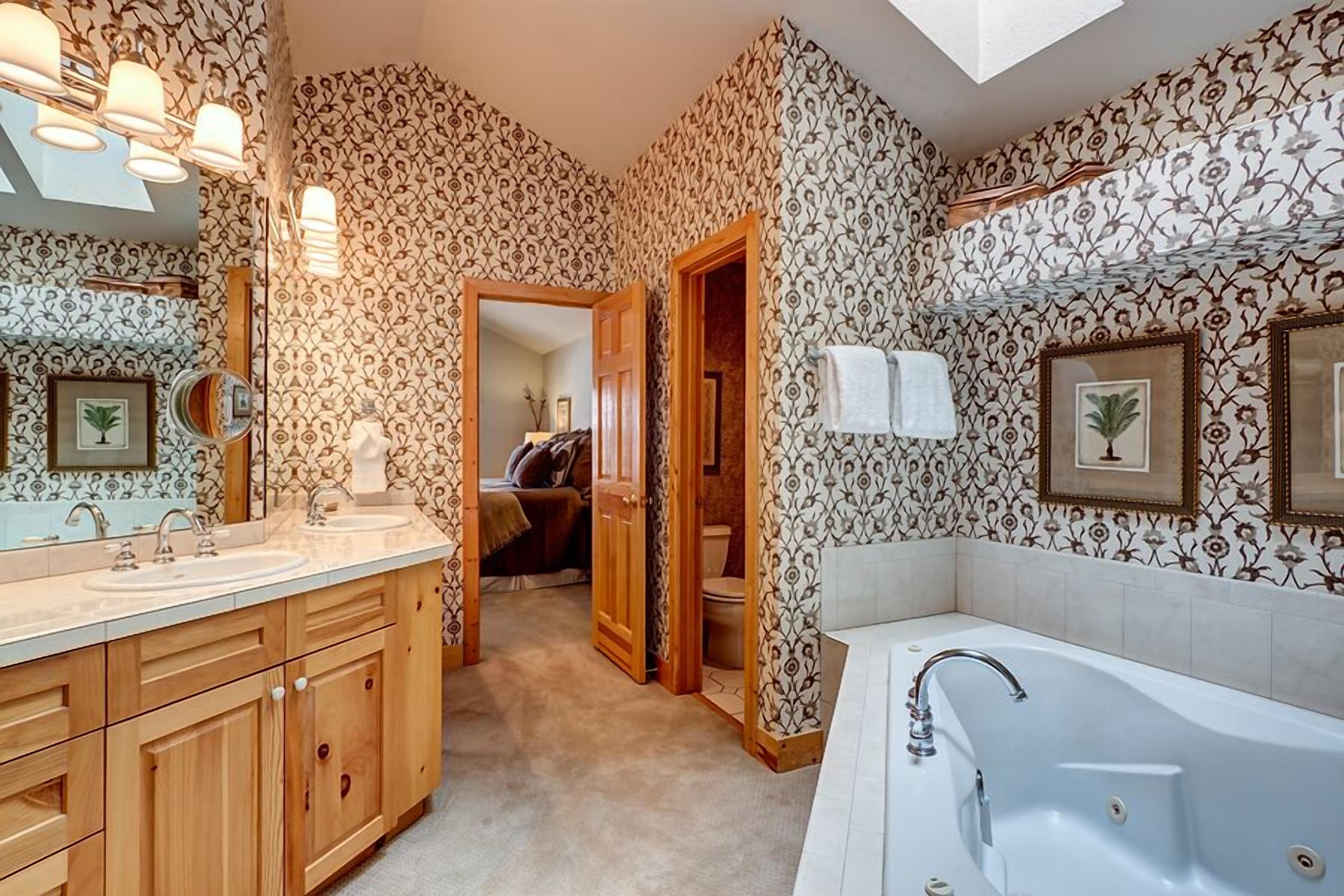 A bathroom with a large bathtub, wooden cabinets, and a mirror.