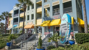 Een meerhoog hotel met balkons, palmbomen en een display met surfplanken.
