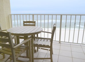 Varanda com mesa e cadeiras com vista para uma praia.