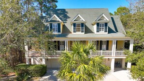 A two-story house with a porch, a driveway, and a palm tree in the front yard. - 3 Surf Watch Way, Pool, Hot Tub, Close To Beach, Free Golf (Hilton Head Island)