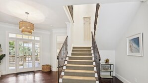 A staircase with a dark wooden handrail and beige carpeted steps, leading to a landing with a woven light fixture. - 3 Surf Watch Way, Pool, Hot Tub, Close To Beach, Free Golf (Hilton Head Island)