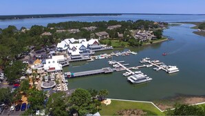 An aerial view of a marina with boats docked, a large building with multiple decks, and surrounding greenery. - 233 Beachside Home- Large 4 Bedroom Homes with Heated Community Pool (Hilton Head Island)