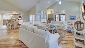 A spacious living room with a large white sofa, a coffee table, and a dining area with a white table and chairs. - 233 Beachside Home- Large 4 Bedroom Homes with Heated Community Pool (Hilton Head Island)