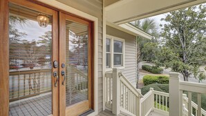 A wooden door with a keypad lock, a white porch railing, and a view of a residential street with houses and trees. - 233 Beachside Home- Large 4 Bedroom Homes with Heated Community Pool (Hilton Head Island)