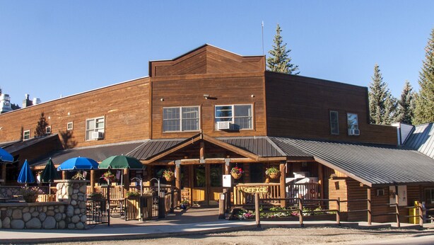 A wooden building with a sign reading "OFFICE" and a covered outdoor seating area with umbrellas. - Hotel Style Lodge Room w/Kitchenette (Almont)