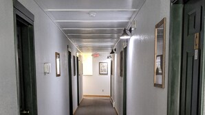 A long, narrow hallway with carpeted floors and doors on both sides. - Hotel Style Lodge Room w/Kitchenette (Almont)