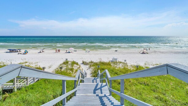 Un escalier en bois mène à une plage d’où l’on a une vue dégagée sur l’océan.