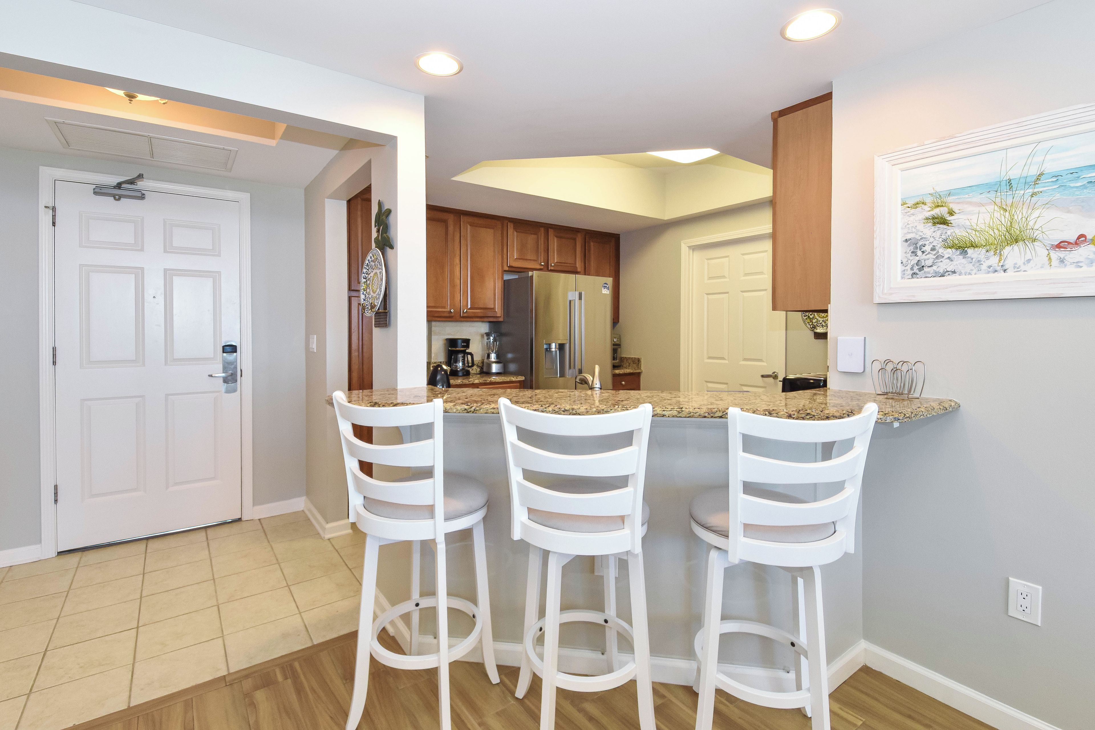 A kitchen with a bar area, wooden cabinets, and a painting on the wall.