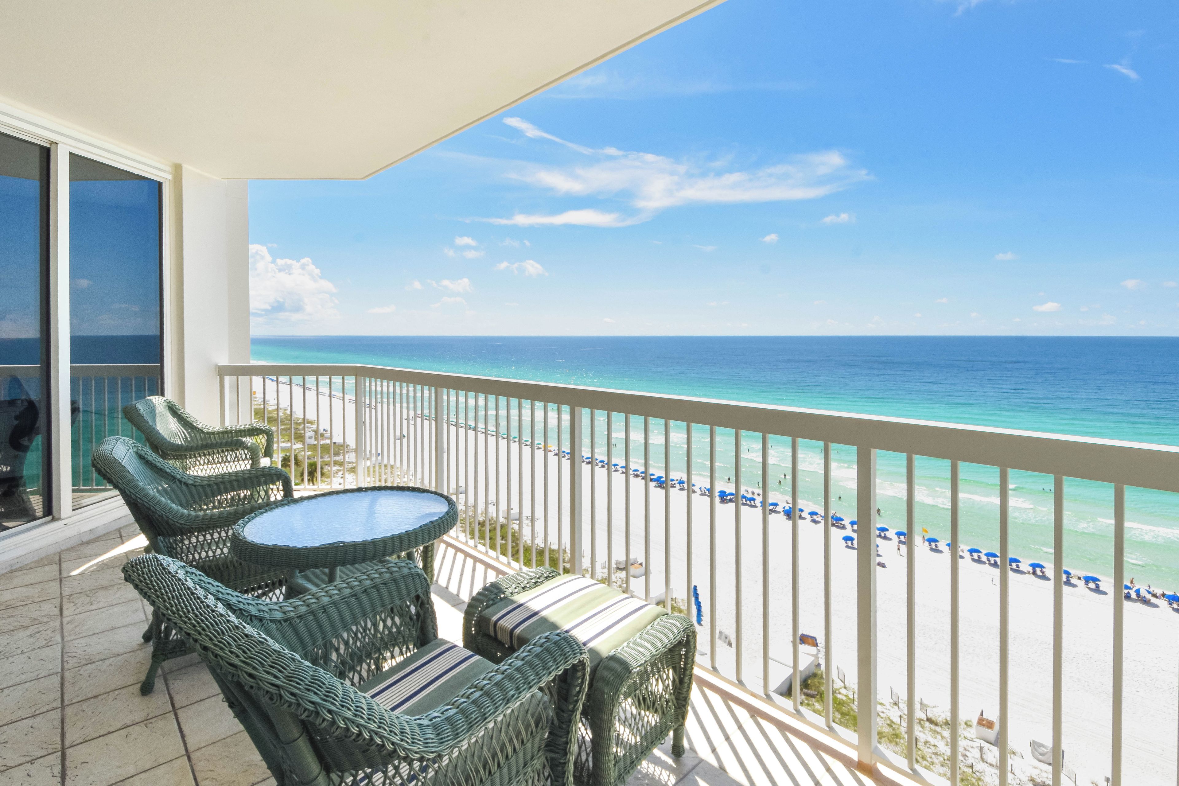 A balcony with wicker furniture and a view of the beach.