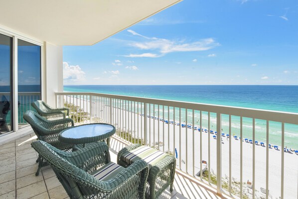 A balcony with wicker furniture and a view of the beach.