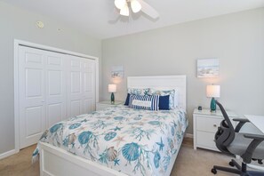 Quarto com cama, escrivaninha, cadeira e duas luminárias de parede.