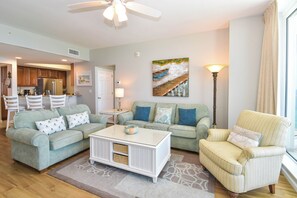 A living room with a sofa, armchair, coffee table, and a painting on the wall. - Tropical Beachfront Condo w/ Private Balcony & Stunning Gulf Views in Destin! 🐬 (Destin)