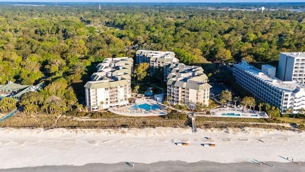 A coastal hotel complex with multiple buildings, a beachfront, and a swimming pool.