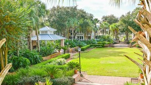 Un exuberante jardín con césped cuidado, senderos de ladrillo y diversas plantas tropicales.