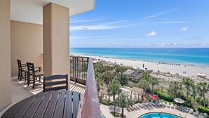 Un balcon avec vue sur une plage et une piscine.