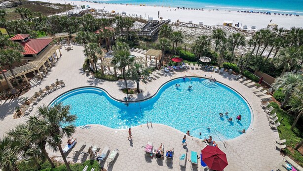 Un complexe hôtelier doté d’une grande piscine, d’un accès à la plage et de palmiers.