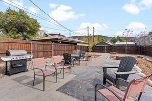 Un jardin avec un barbecue, des chaises et une table.