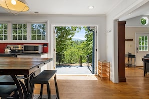 A modern kitchen with a view of a green landscape through an open door.