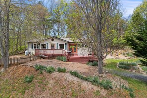 A rustic cabin with a wooden deck, surrounded by trees and a landscaped garden. - Pet-Friendly Mountain Views + Biltmore Pass | 20 Mins to Asheville (Weaverville)