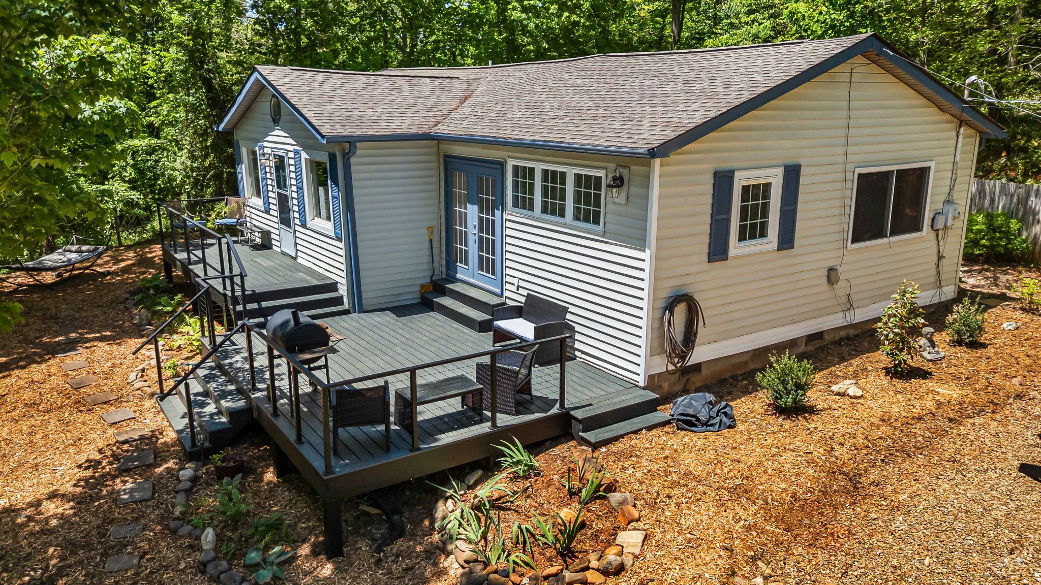 A single-story house with a deck, a front door, and a small porch area.