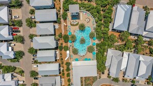 Una vista aerea di una zona residenziale con diverse case, una piscina e un giardino curato.