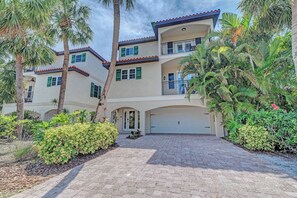 A two-story house with a driveway, palm trees, and a garage.