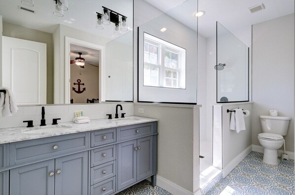 Un baño moderno con un tocador espacioso, ducha e inodoro.