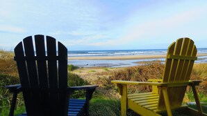 Dos sillas Adirondack mirando una playa con vistas al océano.